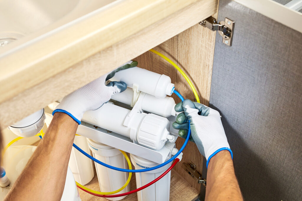 Plumber hand in gloves replace water filter cartridges at kitche