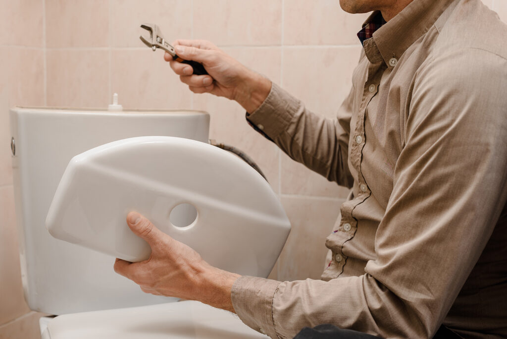 Professional plumber or owner repairing the toilet cistern in th